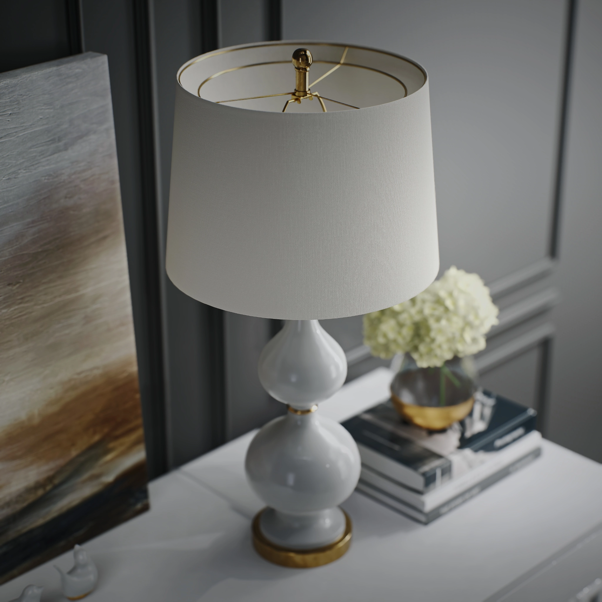 View from above of a white gourd-shaped table lamp with a gold base beside books and hydrangeas